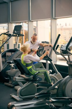 Eğitim sırasında yardım ve rehberlik. Yaşlı adamın yaşlı kadına staj bisikleti eğitimi için yardım etmesi. Yaşlıların konsepti, spor, aktif yaşam tarzı, sağlık