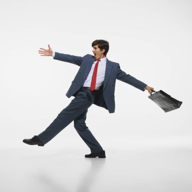 Mavi takım elbiseli ve kırmızı kravatlı neşeli bir işadamı, kollarını uzatıyor, evrak çantasını beyaz arka plana doğru tutuyor. Motivasyon ve enerji. İş kavramı, başarı, başarı