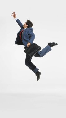 Mavi takım elbiseli ve kırmızı kravatlı bir işadamı evrak çantasıyla enerjik bir şekilde sıçrıyor, hırsını, enerjisini ve işinde ilerlemesini resmediyor. İş kavramı, başarı, başarı, ilerleme