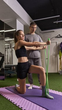 Fizyoterapistin hastaya yeşil direnç bantlarıyla güç egzersizleri yapmasını öğrettiği rehabilitasyon seansı. Rehabilitasyon, iyileşme, sağlık, fizik tedavi