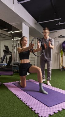 Rehabilitasyon sırasında fizyoterapist gözetiminde pilates halkası kullanan bir kadın hasta. Rehabilitasyon, iyileşme, sağlık, fizik tedavi