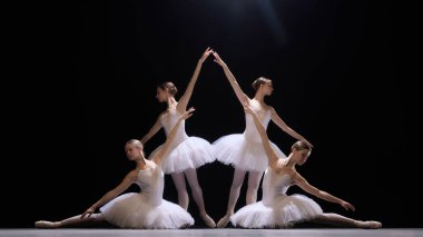 Sahnede karmaşık ve dramatik bir formasyon sergileyen bale dansçıları. Sanatsal ve hassas bir şekilde dans ediyorlar. Zarif dansın güzelliğini gösteriyorlar. Klasik dans, sanat, hareketlerin güzelliği kavramı