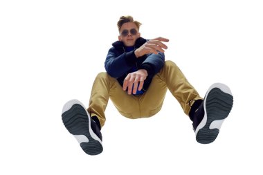 Gözlüklü, mavi ceketli ve hardal pantolonlu şık bir gencin dinamik duruşu. Şehir tarzı, modern, modaya uygun görünüm. Moda kavramı, gençlik kültürü, yaşam tarzı