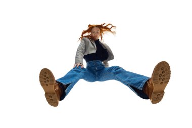 Kırpılmış ceket giyen, beyaz stüdyo geçmişine karşı kot giyen parlak kızıl saçlı genç bir kadın. Gençlik tarzı. Alt manzara. Moda anlayışı, gençlik kültürü, yaşam tarzı, günlük giysiler.