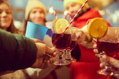 Portakal dilimleri ve çizgili kamışlarla sıcak şarap kadehlerini yakın plan çek. Bir grup arkadaş dışarıda toplanıp kış tatilini kutluyorlar. Kış tatili kavramı, Noel, gelenekler