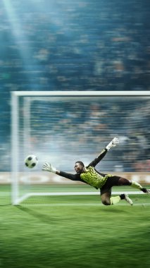 Hareketli kaleci hızlı hareket eden futbol topunu yakalıyor, parlak ışıklandırılmış bir stadyumda tezahürat yapan kalabalığın bulanık arka planıyla. Üç boyutlu arena. Spor, oyun, turnuva, yarışma kavramı