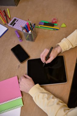 Stylus 'u tablet üzerinde kullanan kişinin odaklanmış görüntüsü, yaratıcılığı ve teknolojik bütünleşmeyi sembolize ediyor. İş kavramı, modern teknolojiler, dijital sanat, yaratıcı