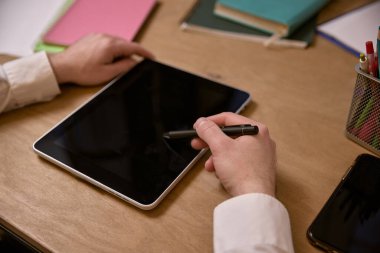 Stylus 'u tutan ve masanın üzerine yerleştirilmiş ofis malzemeleri ve not defterleriyle etkileşime geçen eller. İş kavramı, modern teknolojiler, dijital sanat