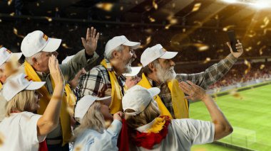 Yaşlılar, parlak ışıklandırılmış stadyumda İspanyol bayraklı futbol fanatikleri neşeli grup selfie 'si için poz veriyor. Yan görüş. - Zafer. Şampiyonluk konsepti, oyun etkinliği, yarışma, turnuva