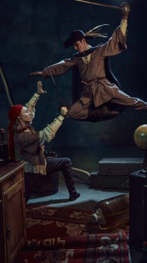 Antika korsanlar gibi giyinmiş, bandana ve şapka takmış, eskimiş halı, mobilya ve bavul gibi arka planda kılıçlarla dinamik bir şekilde savaşan iki tıp adamı. Tarih kavramı, fantezi