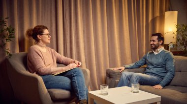 Pembe kazaklı bir psikolog ve mavi kazaklı bir müşteri sıcak ışıklı bir odada karşılıklı oturup sohbet ediyorlar. Psikoloji kavramı, yardım, terapi