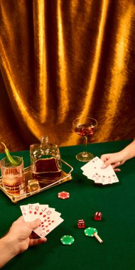 Hayat fotoğrafçılığı, kağıt oynayan adam ve kadın viski bardakları, poker fişleri ve altın perdeye karşı zar ile masada oturuyor. Lüks ve dram. Parti anlayışı, kutlama, yüksek sosyete