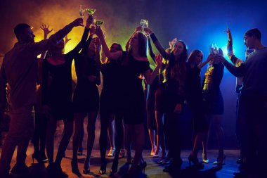 Bir grup genç, erkek ve kız, öğrenciler gece kulübünde eğleniyor, partiye katılıyor, renkli neon ışıkların altında dans ediyorlar. Dinamik müzik, şenlik havası. Gençlik kültürü, eğlence anlayışı