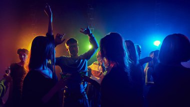 Tatil kutlaması. Gece kulübüne katılan genç insanlar, parti neon ışıkların altında neşeyle dans eden, eğlenen ve rahatlatan. Gençlik kültürü, eğlence, keyif kavramı