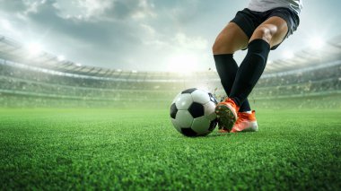 Top sürme hareketi. Beyaz formalı futbolcu, siyah şortlu yeşil sahada topa vuruyor. 3D stadyum, parlak ışıklar, hız, hassasiyet. Spor anlayışı, rekabet, hedefler.