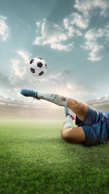 Mavi üniformalı futbolcu mavi gökyüzünün altında yeşil alana çarpıcı bir tekme atıyor. Galibiyet golü. Odaklanma, hassasiyet, beceri. Spor, rekabet, gol, ustalık, turnuva kavramı