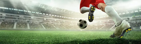 Powerful strike. Soccer player in red shorts making jump kick towards ball in stadium under sunlight. 3D model of arena. Speed, motion, goal attempt. Concept of sport, competition, winning moment.