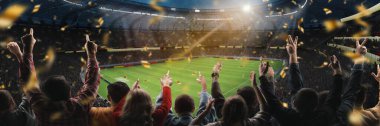 Zafer anı. Futbol taraftarları golü kutluyor, stadyumda düşen konfetilerle el kaldırıyorlar. Joy, heyecan ve takım ruhu. Kutlama, galibiyet, şampiyonluk, spor tutkusu kavramı.