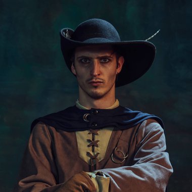 Cesur bir adamın portresi, ortaçağ korsanı tüylü bir şapkayla koyu yeşil renkli arka plana yoğun bir şekilde bakıyor. Entrika ve strateji kavramı, tarih, keşif, güven