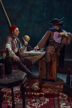 Erkekler, korsanlar karanlık arka planda eski dünya ve denizcilik araçlarıyla kağıt oynuyorlar. Tarihsel macera kavramı, kumar, takım çalışması, arkadaşlık, eğlence