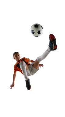 Oğlanın dinamik görüntüsü, turuncu formalı futbolcu ve uzun bacaklı beyaz şortlu tekmeleyen top, beyaz stüdyo geçmişine karşı yetenek gösteriyor. Spor, eğitim, rekabet, oyun kavramı