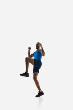 Duygusal adam, zaferi kutlayan profesyonel koşucu, beyaz stüdyo arka planında izole edilmiş mutluluğa atlayan. Spor anlayışı, rekabet, dayanıklılık, atletizm, spor yaşam tarzı. Boşluğu kopyala