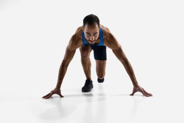 Odaklanmış ve kararlı bir adam, koşucu başlangıç pozisyonunda, koşmaya hazır ve beyaz stüdyo arka planında izole edilmiş olarak kazanmaya hazır. Spor, rekabet, dayanıklılık, atletizm, spor yaşam tarzı kavramı.