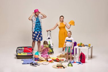 Aile yaz şapkaları, güneş gözlükleri, aksesuarları kontrol etmek, bavulları hazırlamak, yaz gezisine hazırlanmak. Parlak kıyafetler, plaj malzemeleri. Eğlence, tatil, macera, turizm kavramı