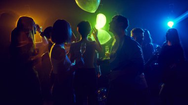 Neşeli gençlerden oluşan bir grup renkli neon ışıkları olan canlı neon ışıklı bir kulüpte kutlama yapıyorlar. Neşeli ve tasasız atmosfer, bağ ve eğlence. Gençlik kültürü kavramı