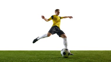 Sahada siyah şortlu, sarı formalı, odaklanmış erkek futbolcu, beyaz arka planda topa vuruyor. Spor, eylem, rekabet, oyun, aktif yaşam tarzı kavramı