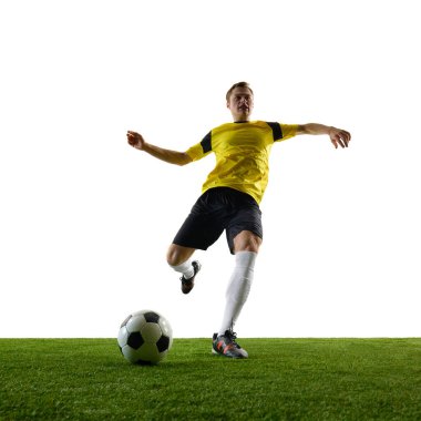 Genç adamın alttaki görüntüsü, kararlı futbolcu aktif olarak top sürüyor, odaklanma ve beyaz arka plana karşı motivasyon ile oynuyor. Spor, eylem, rekabet, oyun, aktif yaşam tarzı kavramı