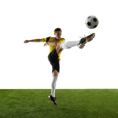 Yoğunlaşmış genç bir adam, futbol, oyun sırasında hareket eden bir atlet, antrenman, uzun bacaklı bir top, beyaz stüdyo arka planına karşı. Spor, eylem, rekabet, oyun, aktif yaşam tarzı kavramı