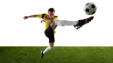 Odaklanmış genç bir adam, futbolcu akrobatik yüksek tekme atıyor, bacağını topa doğru kaldırıyor, beyaz arka plana yoğun bir şekilde odaklanıyor. Dinamik hareket kavramı, rekabet, eğitim.