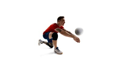 Genç erkek voleybol oyuncusunun dinamik görüntüsü, üniformalı sporcu topa vuruyor, beyaz stüdyo arka planında antrenman yapıyor. Spor, rekabet, enerji, aktif yaşam tarzı, kararlılık kavramı.