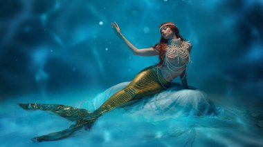 Zarif kızıl saçlı kadın, yumuşak kumaşın üzerinde uzanan altın kuyruklu denizkızı, gerçek üstü bir okyanus ortamında lüks inciler ve saçlar takıyor. Mitoloji kavramı, gizem, güzellik, rüya gibi hayal