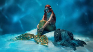 Sualtı prensesi, incili kızıl saçlı kadın ve rüya gibi okyanus sahnesinde zarifçe poz veren altın kuyruk. Güzellik kavramı, büyü, mitoloji ve fantezi fotoğrafçılık..