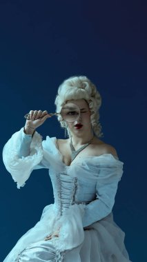 Esprili bak. Büyütücü gözlü barok tarzı bir kadın. Mavi arka planda asil bir karakter gibi giyinmiş. Dönem, mizah, görsel metafor, klasik zarafet, portre çalışması karışımı.