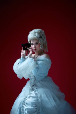 Gizemli güzellik. Barok tarzı bir kadın zarif bir elbise içinde kendine güvenen bir bakışla siyah maskeyi kaldırıyor. Tarihsel portre, maskeli balo, drama, kadınlık, gizem kavramı.