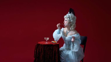 Soylu hoşgörü. Süslü tabaktan havyar tatmak için peruk tozu kullanan ortaçağ tarzı genç bir kadın. Lüks, zevk, güzellik standartları, zaman zıtlığı, zarafet, kraliyet portresi, hiciv kavramı.