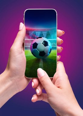 Stadyumda futbol topuyla akıllı telefon tutan ve açık hava maçı sırasında arka planda duran kişi. Bileşik kolaj. Spor, oyun, bahis, yarışma kavramı