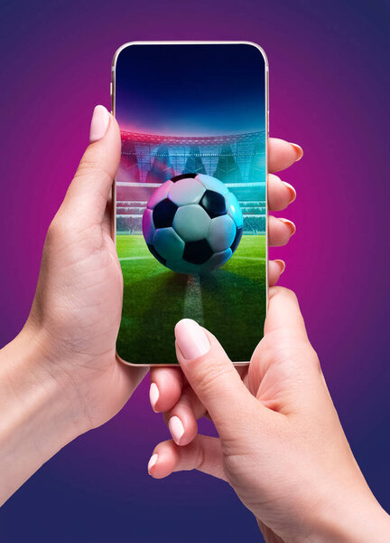 Person holding smartphone with soccer ball on stadium and filled stands in the background during open air match event. Composite collage. Concept of sport, game, betting, competition