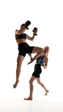 Bir bayan sporcu, beyaz arka planda izole bir şekilde idman yaparken rakip bedene diz darbesi indiriyor. MMA, Tayland boksu, dövüş sanatları, güç, dövüş sporu, çeviklik kavramı