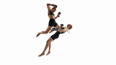 Beyaz arka planda güç ve hız ile senkronize olarak yakalanan kadın MMA dövüşçüleri arasında çarpıcı bir hava savaşı var. Tayland boks, spor, rekabet, hareket, aksiyon, uçan tekme kavramı