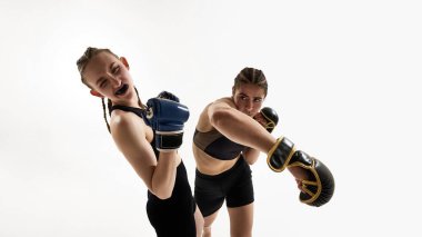 Şiddetli savaş anı. Genç kadın, Taylandlı boks atleti beyaz arka plandaki dinamik boks eğitimi sırasında rakibine güçlü bir yumruk atıyor. MMA kavramı, spor, dövüş sporu, güç