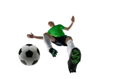 Düşük açılı genç adam, spor üniforması giymiş, futbolcu eğitimi almış, beyaz stüdyo arka planına karşı topa vuruyor. Profesyonel spor, antrenman, turnuva, enerji kavramı. Ad