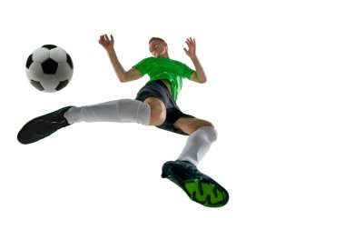 Düşük açılı atletik bir adam, spor üniforması giymiş, futbolcu, beyaz stüdyo arka planına karşı topa vurmak için ayağa kalkıyor. Profesyonel spor, antrenman, turnuva, enerji kavramı. Ad