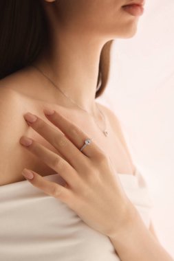 Nişan yüzüklü, gümüş kolyeli, narin aksesuarlarla ışıldayan yumuşak güzellik ve romantik cazibeli bir kadın portresi. Mücevher, lüks, aksesuar kavramı.