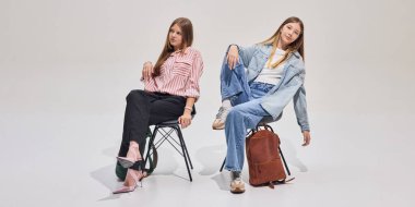 Sırt çantalı, rahat ve kendine güvenen, yeni okul gününe ya da ders çalışmaya hazır iki şık öğrenci. Eğitim kavramı, öğrenciler, yaşam tarzı, tavır.