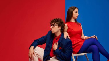 Genç bir adam ve kadın, koyu kırmızı bir mavili çift şık retro kıyafetler ve kendine güvenen ifadelerle poz veriyorlar. İnsan duyguları, ilişkisi, yaşam tarzı kavramı