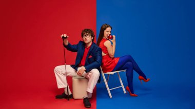 Kırmızı mavi yazlık giysiler içinde kırmızı mavi arka planda çıplak ayakla gülümseyen çift. İnsan duyguları kavramı ilişki yaşam tarzı